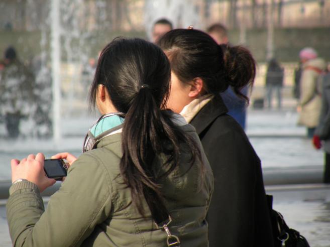  jeunes femmes assises au pied de la pyramide du Louvre